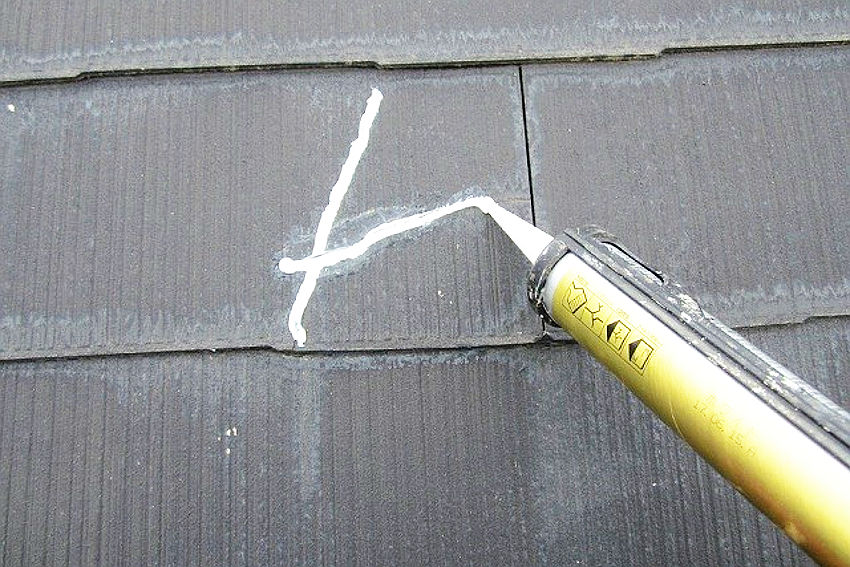 割れている部分をコーキングで補修工事している屋根部分