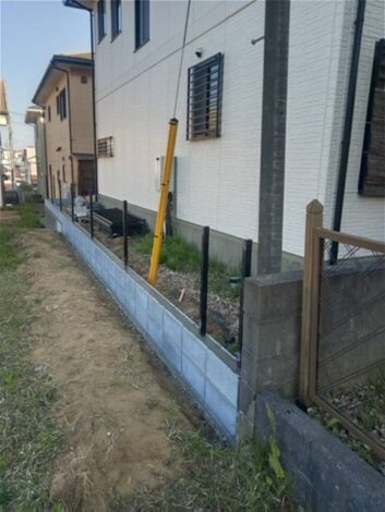ブロックを積みフェンスの支柱を立てた擁壁上部
